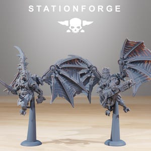 May include: Two grey miniature figures with mechanical wings and weaponry, mounted on grey stands. The figures are detailed with armour and intricate designs. The text "STATIONFORGE" and a skull logo are at the top.