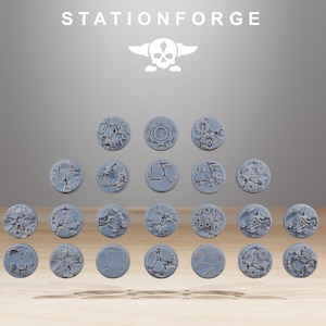 Op de afbeelding: Een verzameling grijze, ronde miniatuur bases met verschillende texturen, waaronder gebarsten aarde en mechanische details. De bases zijn in rijen gerangschikt, met het woord "STATIONFORGE" en een schedellogo bovenaan.