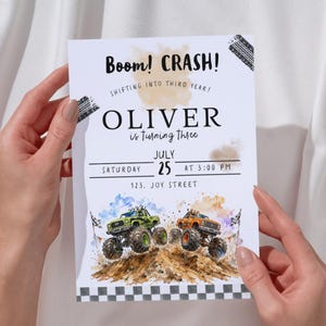 May include: A white invitation with the text "Boom! CRASH!" and "OLIVER is turning three." The invitation features a watercolor illustration of two monster trucks. The date is July 25th at 3:00 PM.