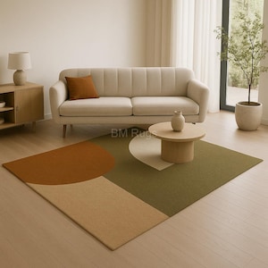 Op de afbeelding: Een modern vloerkleed met een geometrisch ontwerp in bruin, beige en groen. Het vloerkleed heeft grote halve cirkel- en rechthoekige vormen, wat een eigentijdse uitstraling aan de woonkamer geeft.