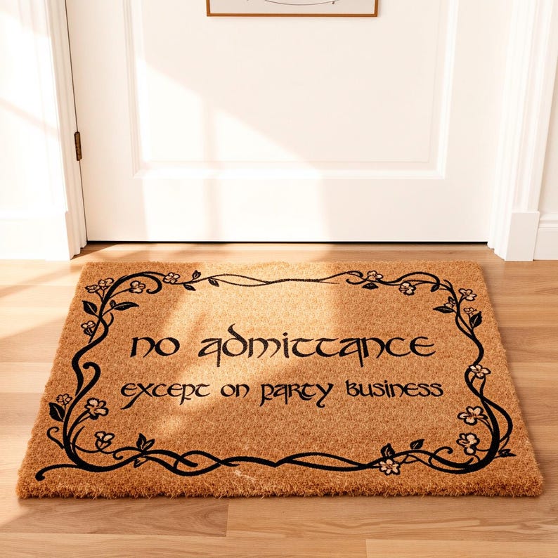 May include: A rectangular doormat made of natural coir fiber. The mat features the words "no admittance except on party business" in black, framed by a decorative floral border. Placed in front of a white door.