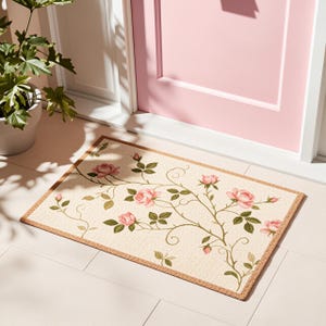 May include: A rectangular doormat with a cream-coloured base and a brown border. The surface features a printed pattern of climbing rose vines with soft pink rose blossoms, green leaves, and thin brown stems extending across the mat.