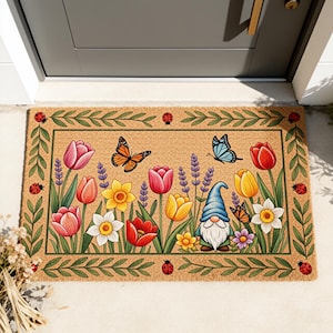 Può includere: Un zerbino rettangolare con un design a giardino primaverile. Il tappeto presenta tulipani, narcisi e lavanda colorati, insieme a farfalle, coccinelle e uno gnomo. Il bordo è un motivo di foglie verdi su sfondo beige.