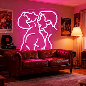 May include: A brown leather sofa is positioned below a large pink neon sign showing two figures. The room has a vintage feel, with film posters and a record player. A floor lamp provides warm lighting.