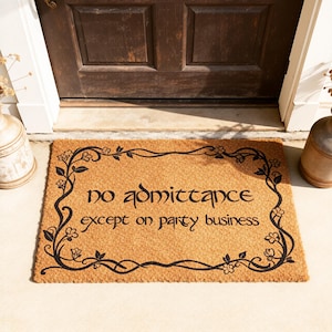 May include: A rectangular doormat made of natural coir fiber. The mat features the text "no admittance except on party business" in black script, framed by a black floral border. The mat is placed in front of a brown door.