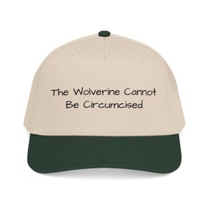 May include: A baseball cap with a cream-coloured crown and a dark green brim. The cap features the text "The Wolverine Cannot Be Circumcised" in black, centred on the front.