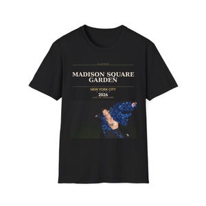 May include: Black t-shirt featuring a graphic of a performer in a blue sequined outfit. The shirt includes the text "SUMMER MADISON SQUARE GARDEN NEW YORK CITY 2026 LIVE IN CONCERT" in a gold font.