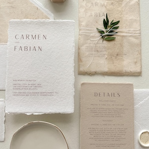 Pu&ograve; includere: Elegante suite di inviti di nozze con carta fatta a mano con testo in rilievo marrone. Include un portagioie, un rametto di verde e un piattino. Il testo recita "Carmen und Fabian" e i dettagli del matrimonio.