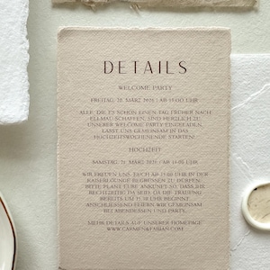 Pu&ograve; includere: Un biglietto d'invito beige con la parola "DETAILS" in un carattere marrone scuro. Il biglietto include il testo su una festa di benvenuto e i dettagli del matrimonio, con date e orari. Il biglietto &egrave; circondato da carta strutturata.