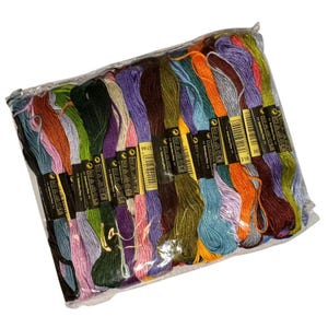 May include: A clear plastic bag containing a selection of embroidery floss in a variety of colours. The floss includes shades of green, purple, orange, blue, and brown. Each skein has a black and yellow label. The floss is densely packed.