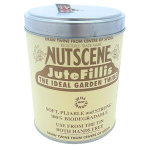 May include: A beige cylindrical tin of Nutscene Jute Fillis garden twine, with brown text and graphics. The text includes "Nutscene" and "Jute Fillis", and "The Ideal Garden Twine". A small Union Jack flag is on the lid. The tin is designed to dispense twine.