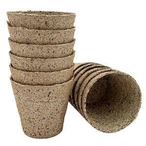 May include: A collection of small, brown, biodegradable plant pots. The pots are made of a textured, fibrous material and are cone-shaped with a wide opening. Additional pots are visible to the right, also brown and cone-shaped.