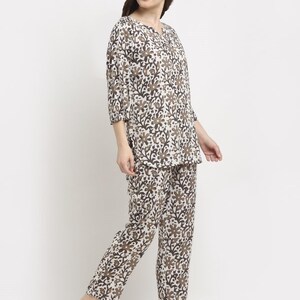 May include: A two-piece pajama set featuring a floral pattern in shades of brown and white. The top has a V-neck and three-quarter sleeves. The pants are long and straight-legged. The fabric appears to be lightweight and comfortable.