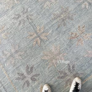 Könnte beinhalten: Hellblauer Teppich mit einem floralen Muster in Beige- und Grautönen. Der Teppich hat einen Used-Look und einen Rand. Der Text "VTRugs" ist auf dem Teppich zu sehen.