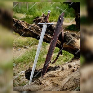 Puede incluir: Una espada medieval con una larga hoja de acero de doble filo y un mango envuelto en cuero marrón. La espada descansa sobre un tronco de madera desgastado, acompañada de una vaina de cuero marrón. La hoja mide unos 91 cm.