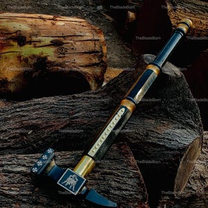 May include: A black and gold battle hammer with a detailed design. The hammer features a square head with a cross design and a rectangular emblem with a horse and rider. The handle is black with gold accents.