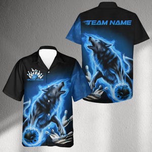 May include: Black bowling shirt with a blue wolf design. The shirt features a howling wolf with a bowling ball and pins, surrounded by blue flames. The text "TEAM NAME" is on the back, and "YOUR NAME" is above the bowling pins.