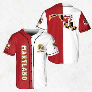 Puede incluir: Una camiseta de béisbol roja y blanca con la palabra "MARYLAND" en letras doradas en la parte delantera. La camiseta presenta la bandera y el sello del estado de Maryland. La parte trasera de la camiseta muestra un mapa de Maryland.