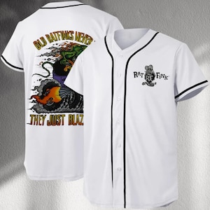 May include: White baseball jersey with black trim and buttons. The front features a Rat Fink graphic and text. The back displays a colorful graphic with the text "OLD RATFINKS NEVER... THEY JUST BLAZ."