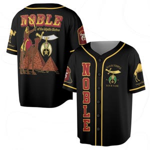 May include: Black baseball jersey with gold trim and buttons. The front features the word "NOBLE" in red, and the back displays a camel and pyramid graphic with the text "NOBLE of the Mystic Shrine".