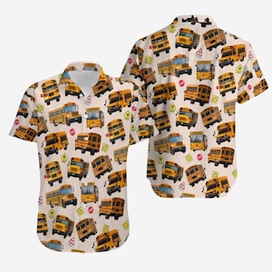 Puede incluir: Camisa de manga corta con un estampado repetido de autobuses escolares amarillos y señales de cruce escolar sobre un fondo beige claro. La camisa tiene un cuello clásico y un corte relajado.