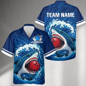 Op de afbeelding: Blauw bowling shirt met een haaienontwerp. Het shirt heeft een bowlingbal in de bek van de haai, met de tekst "YOUR NAME" en "TEAM NAME". Het shirt heeft witte strepen op de mouwen.