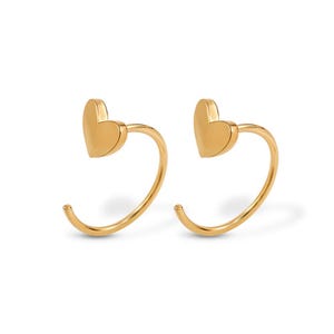 Könnte beinhalten: Ein Paar goldfarbene Ohrringe. Jeder Ohrring hat ein herzförmiges Design an der Oberseite, verbunden mit einem gebogenen, offenen Bügel. Die Ohrringe werden vor einem weißen Hintergrund präsentiert, der ihre polierte Oberfläche hervorhebt.