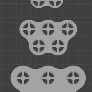 Puede incluir: Tres formas abstractas grises estilizadas, cada una con recortes circulares con un dise&ntilde;o de cruz. Las formas est&aacute;n dispuestas verticalmente sobre un fondo de cuadr&iacute;cula gris oscuro. La forma superior tiene seis recortes, la del medio seis y la inferior ocho.