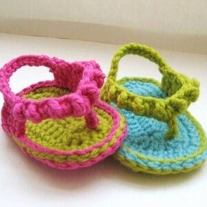 May include: Two pairs of crocheted baby sandals. One pair is pink and green, the other is blue and green.