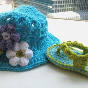 May include: A crocheted blue sun hat with white and purple flowers and a matching pair of green and blue crocheted sandals.