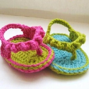 May include: Two pairs of crocheted baby sandals. One pair is pink and green, the other is blue and green.