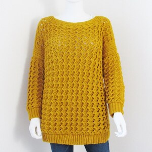 May include: A mustard yellow crochet sweater with a loose fit and long sleeves.