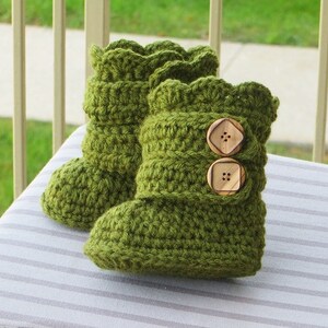 May include: A pair of green crocheted baby booties with wooden buttons.