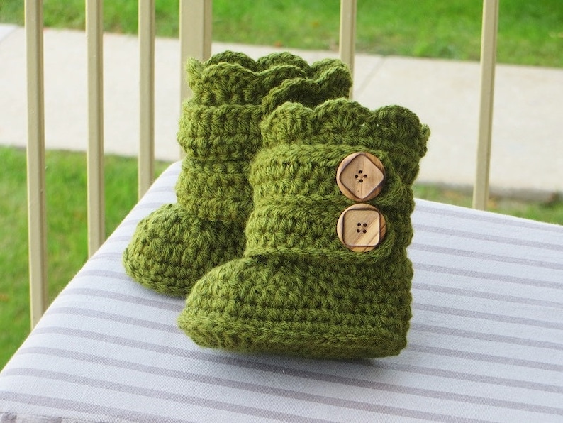 May include: A pair of green crocheted baby booties with wooden buttons.