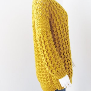 May include: A mustard yellow crocheted sweater with a loose fit and a textured stitch pattern.