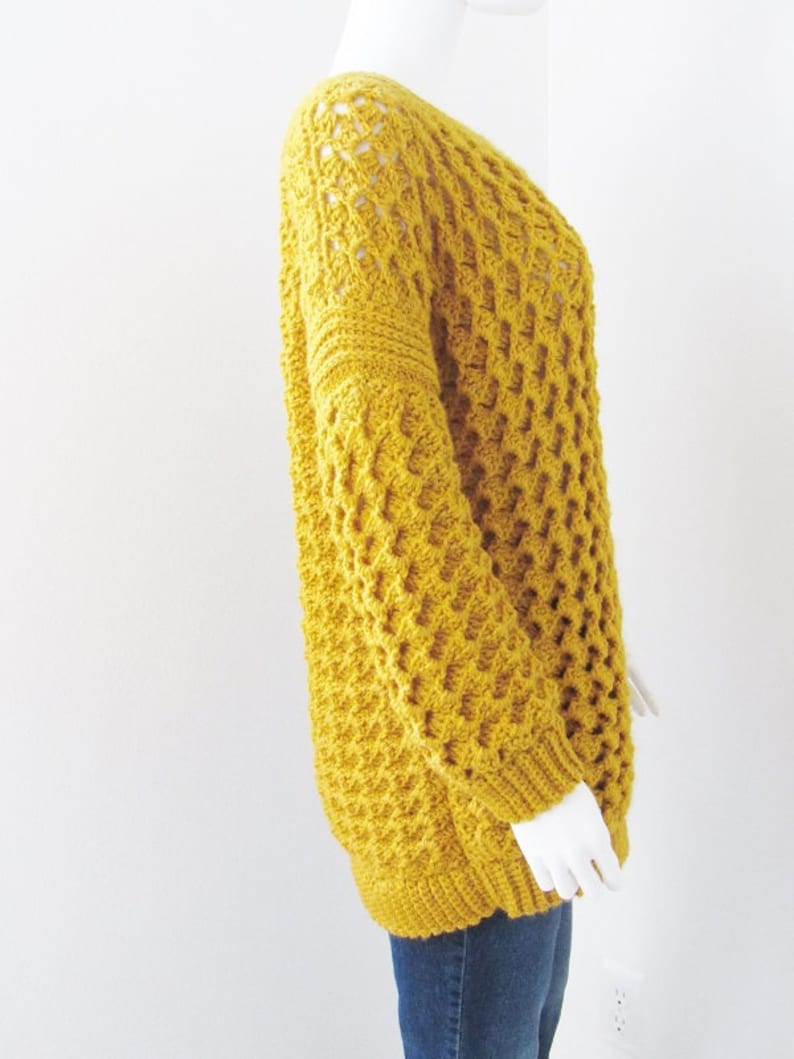 May include: A mustard yellow crocheted sweater with a loose fit and a textured stitch pattern.