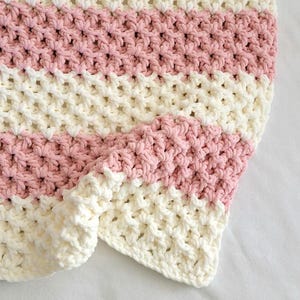 May include: A pink and white striped crocheted blanket with a textured, waffle-like stitch.
