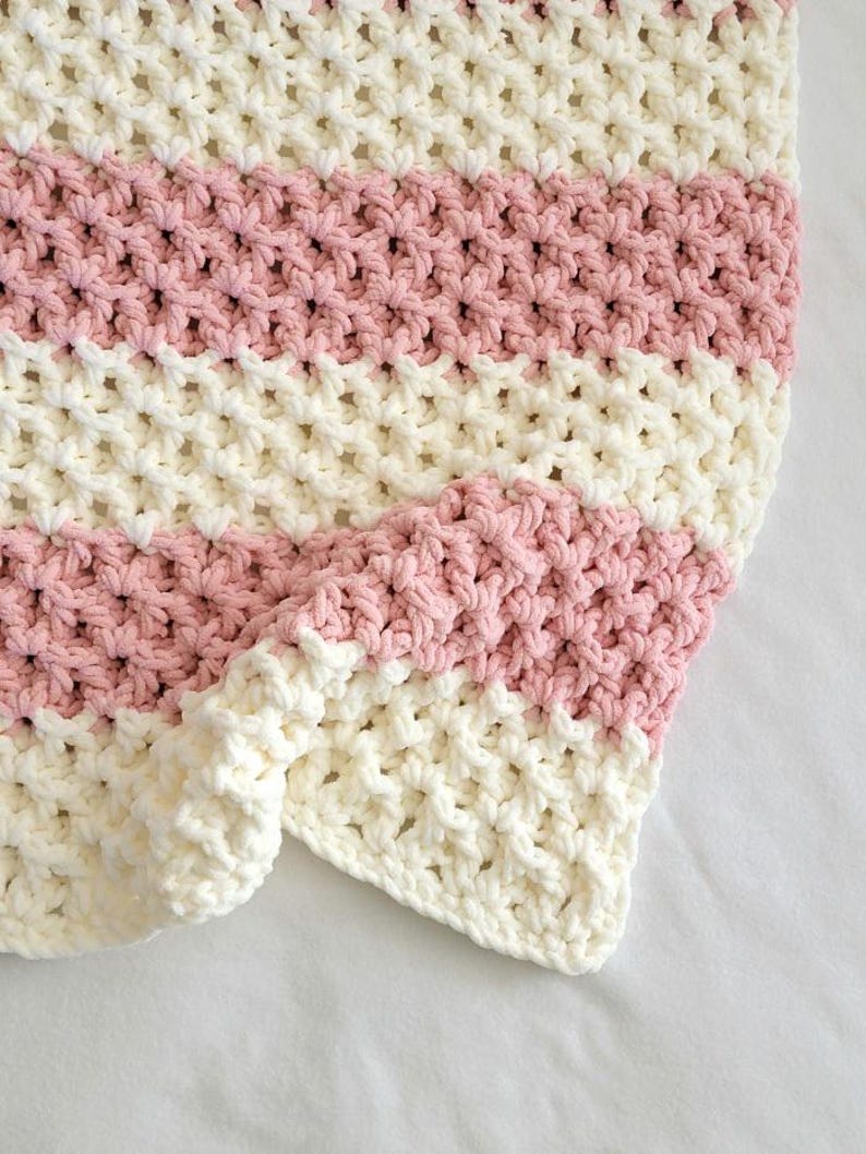 May include: A pink and white striped crocheted blanket with a textured, waffle-like stitch.