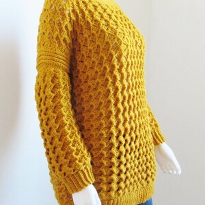 May include: A mustard yellow crocheted sweater with a loose fit and a textured stitch pattern.