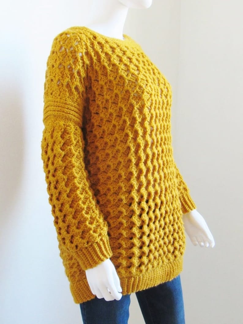 May include: A mustard yellow crocheted sweater with a loose fit and a textured stitch pattern.
