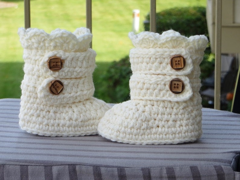 May include: A pair of white crocheted baby booties with brown button accents.