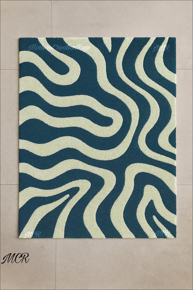 May include: A rectangular rug with a wavy pattern. The rug features a dark blue background with cream-colored, flowing lines. The text "Modern Creation Rugs" and "MCR" are visible.