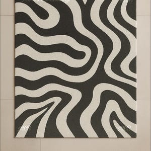 May include: A rectangular rug with a repeating pattern of wavy, cream-colored stripes against a dark gray background. The rug has the text "Modern Creation Rugs" and "MCR" in the corners. This rug is suitable for home decor.