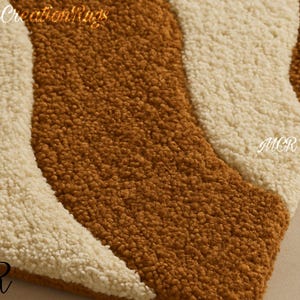 May include: Close-up of a textured rug with a wavy design. The rug features alternating stripes of brown and off-white. The letters "MCR" are visible in the corners and "Modern Creation Rugs" is at the top.