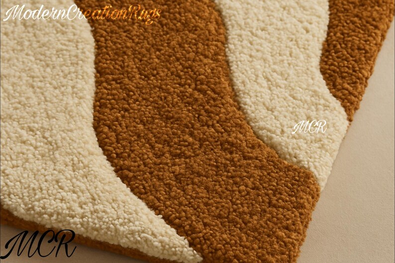 May include: Close-up of a textured rug with a wavy design. The rug features alternating stripes of brown and off-white. The letters "MCR" are visible in the corners and "Modern Creation Rugs" is at the top.