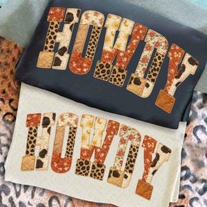 Puede incluir: Dos sudaderas, una azul marino y otra blanquecina, cada una con la palabra "HOWDY" en un diseño de patchwork. Las letras presentan varios patrones, incluyendo estampado de vaca, estampado de leopardo, floral y motivos de sol, con un borde cosido.