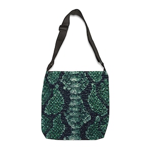 Puede incluir: Bolso de hombro verde y negro con estampado de piel de serpiente. El bolso tiene una correa negra ajustable y forma rectangular. El patrón es una mezcla de escamas verde oscuro y negro.