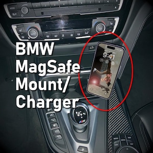 Może przedstawiać: Czarne wnętrze samochodu z telefonem zamontowanym na ładowarce MagSafe. Telefon wyświetla zdjęcie osoby. Widoczny jest tekst "BMW MagSafe Mount/Charger".