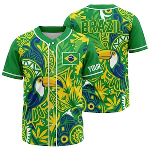 May include: Green baseball jersey with a vibrant Brazilian-themed design. The jersey features a toucan, the Brazilian flag, and the word "BRAZIL" on the back. The design incorporates yellow and blue accents.