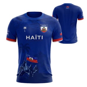 May include: A blue short-sleeved t-shirt featuring the text HAÏTI, a palm tree icon, and a graphic of people raising the Haitian flag. The shirt includes the Haitian coat of arms on the chest, red trim on the sleeves, and a rear view showing the flag.